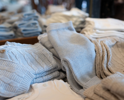Kleidung liegt in Stapeln im Laden von Bambolino in Fulda