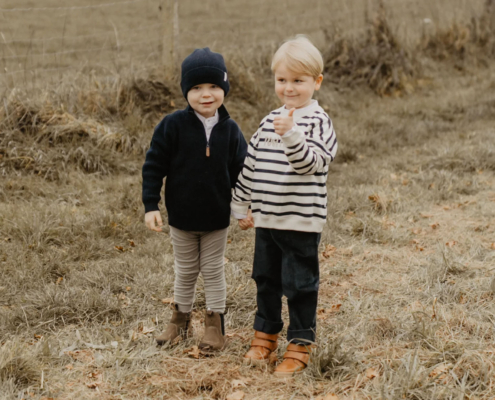 Zwei Jungs stehen in Leevje Herbst-Kleidung auf einem Feld